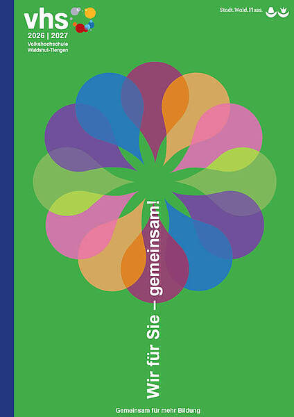 Es handelt sich um das Titelbild des Volkshochschulprogramms 2026/2027 der Volkshochschule Waldshut-Tiengen. Das Bild hat einen leuchtend grünen Hintergrund mit einem dunkelblauen vertikalen Streifen am linken Rand. Oben links befindet sich das Volkshochschul-Logo mit bunten Punkten in Rot, Grün, Gelb und Lila, darunter steht "2026 | 2027" sowie "Volkshochschule Waldshut-Tiengen" in weißer Schrift. Oben rechts ist der Schriftzug "Stadt Wald-Fluss" mit zwei stilisierten Icons platziert. Im Zentrum des Bildes dominiert ein großes, dekoratives Blumenmotiv, das aus zwölf überlappenden, tropfenförmigen Blütenblättern besteht. Diese sind kreisförmig angeordnet und in unterschiedlichen Farben gestaltet: verschiedene Lila-, Blau-, Pink-, Orange-, Gelb-, Beige- und Grüntöne. Die Blütenblätter überlappen sich teilweise und erzeugen einen dynamischen, farbenfrohen Effekt. Vertikal durch die Mitte der Blume verläuft in weißer Schrift der Text "Wir für Sie – gemeinsam!" (von unten nach oben lesbar). Am unteren Bildrand steht der Slogan "Gemeinsam für mehr Bildung" ebenfalls in Weiß.  [1]:  Titelblatt 2026_2027.jpg